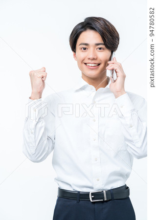 A young man doing a guts pose while making a phone call A young man doing a guts pose while making a phone call 94780582
