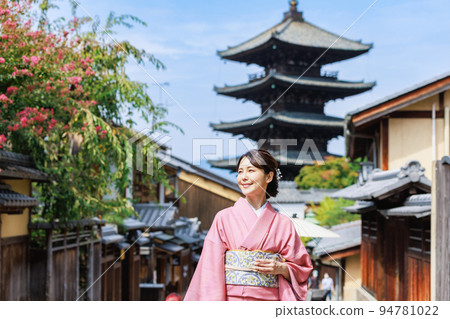 A young woman in a kimono standing with a five-storied pagoda in the background 94781022