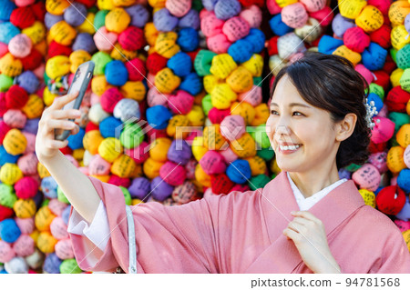 A woman in a kimono taking a selfie at a tourist spot 94781568