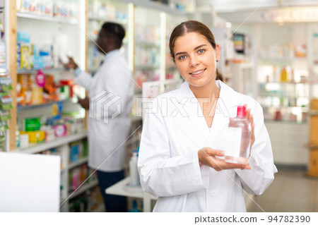 Portrait of a smiling young female pharmacist, demonstrating recently received goods for sale Portrait of a smiling young female pharmacist, demonstrating recently received goods for sale 94782390