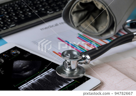 Using the digital tablet, the doctor checks the results of the echocardiography ultrasound of the heart examination in order to prescribe a treatment that is effective for the patient Using the digital tablet, the doctor checks the results of the echocardiography ultrasound of the heart examination in order to prescribe a treatment that is effective for the patient 94782667