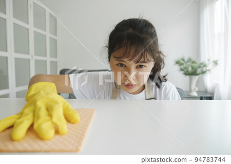 Young woman cleaning table wearing gloves at home. 94783744