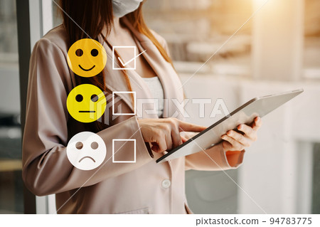 Customer service evaluation concept. woman Show face smile emoticon show on virtual screen from hand.looking at tablet and laptop Customer service evaluation concept. woman Show face smile emoticon show on virtual screen from hand.looking at tablet and laptop 94783775
