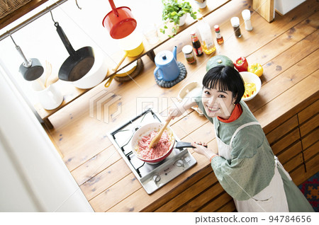 A young woman cooking, looking at the camera, bird's-eye view A young woman cooking, looking at the camera, bird's-eye view 94784656