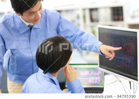 A female designer receiving an explanation of CAD work from a senior employee_4 94785390