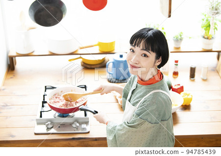 一個年輕女子在做飯，看著相機，鳥瞰圖 94785439