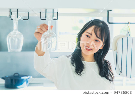 A woman holding a wine glass in the kitchen 94786808