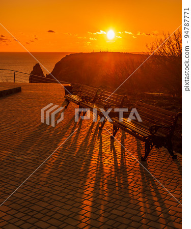 A red burning sunset with the silhouett of a cliff over the sea in park A red burning sunset with the silhouett of a cliff over the sea in park 94787771