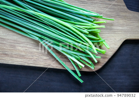 Bunch of chives on a wooden cutting board 94789032