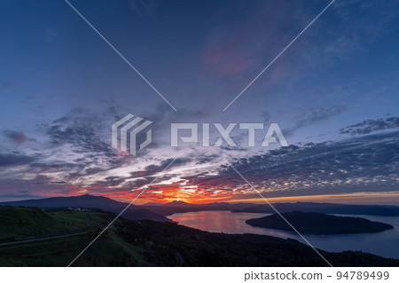 Lake Kussharo seen from Bihoro Pass, the surface of the lake dyed red with the sunrise 94789499