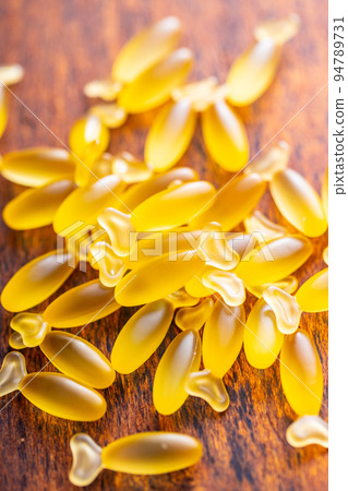 Fish oil capsules. Yellow omega 3 pills on wooden table. Fish oil capsules. Yellow omega 3 pills on wooden table. 94789731