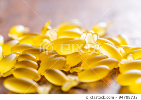 Fish oil capsules. Yellow omega 3 pills on wooden table. 94789732