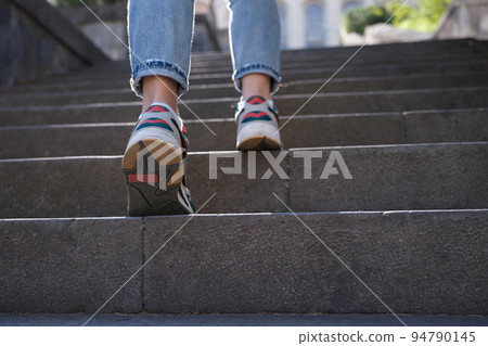 Closup of woman legs in sneakers walking up steps 94790145