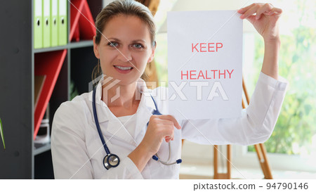 Smiling woman doctor shows inscription keep patient healthy 94790146