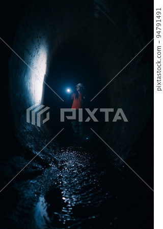 Female digger with flashlight explores the tunnel Female digger with flashlight explores the tunnel 94791491