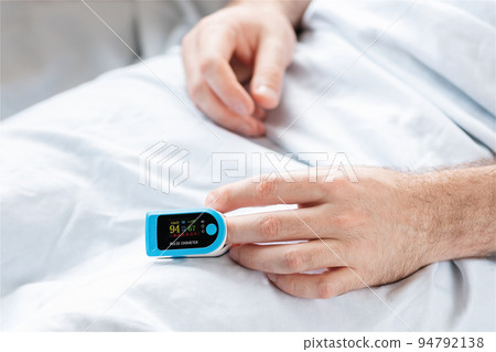 Patient lying at bed with pulse oximeter. Close up of hands. Concept of determination of oxygen in the blood. Treatment in the intensive care unit Patient lying at bed with pulse oximeter. Close up of hands. Concept of determination of oxygen in the blood. Treatment in the intensive care unit 94792138