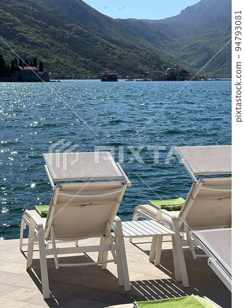 Sun loungers stand on the promenade overlooking the island of Gospa od Skrpjela Sun loungers stand on the promenade overlooking the island of Gospa od Skrpjela 94793081