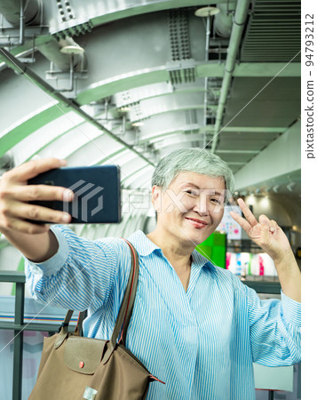 一位 60 歲的成熟亞洲女性寫下智慧型的自我打擊、旅行或觀光探索概念。 一位 60 歲的成熟亞洲女性寫下智慧型的自我打擊、旅行或觀光探索概念。 94793212