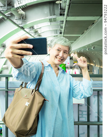 一位 60 歲的成熟亞洲女性寫下智慧型的自我打擊、旅行或觀光探索概念。 一位 60 歲的成熟亞洲女性寫下智慧型的自我打擊、旅行或觀光探索概念。 94793222