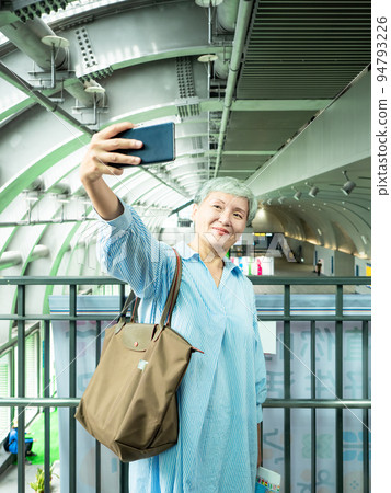 一位 60 歲的成熟亞洲女性寫下智慧型的自我打擊、旅行或觀光探索概念。 一位 60 歲的成熟亞洲女性寫下智慧型的自我打擊、旅行或觀光探索概念。 94793226
