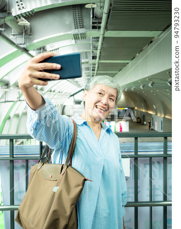 一位 60 歲的成熟亞洲女性寫下智慧型的自我打擊、旅行或觀光探索概念。 一位 60 歲的成熟亞洲女性寫下智慧型的自我打擊、旅行或觀光探索概念。 94793230