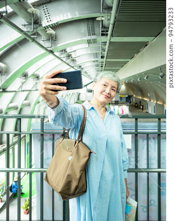 A 60-year-old mature Asian woman writes wisdom-type self-beating, travel or sightseeing exploration concept. 94793233