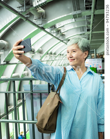 一位 60 歲的成熟亞洲女性寫下智慧型的自我打擊、旅行或觀光探索概念。 一位 60 歲的成熟亞洲女性寫下智慧型的自我打擊、旅行或觀光探索概念。 94793236
