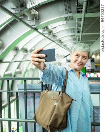 一位 60 歲的成熟亞洲女性寫下智慧型的自我打擊、旅行或觀光探索概念。 一位 60 歲的成熟亞洲女性寫下智慧型的自我打擊、旅行或觀光探索概念。 94793237