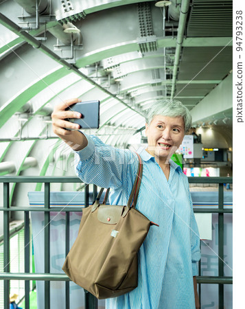 一位 60 歲的成熟亞洲女性寫下智慧型的自我打擊、旅行或觀光探索概念。 一位 60 歲的成熟亞洲女性寫下智慧型的自我打擊、旅行或觀光探索概念。 94793238