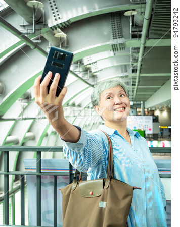 一位 60 歲的成熟亞洲女性寫下智慧型的自我打擊、旅行或觀光探索概念。 一位 60 歲的成熟亞洲女性寫下智慧型的自我打擊、旅行或觀光探索概念。 94793242