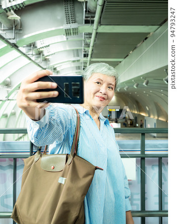 一位 60 歲的成熟亞洲女性寫下智慧型的自我打擊、旅行或觀光探索概念。 一位 60 歲的成熟亞洲女性寫下智慧型的自我打擊、旅行或觀光探索概念。 94793247