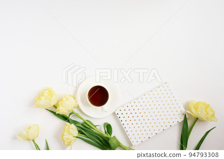 Spring yellow tulips, coffee mug, notebook on a white background. Flat position, top view. Spring yellow tulips, coffee mug, notebook on a white background. Flat position, top view. 94793308