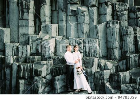 Bride and groom stand on the black rocks of Reynisdrangar in Iceland 94793359