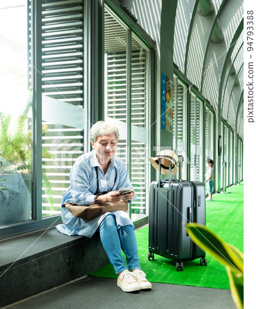 60多歲的亞洲熟年婦女微笑著坐著,身旁有手提箱行李袋和手持登機證與護照,適用於covid19疫情後旅 60多歲的亞洲熟年婦女微笑著坐著,身旁有手提箱行李袋和手持登機證與護照,適用於covid19疫情後旅 94793388