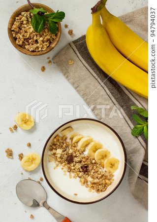 Granola. Granola with yogurt, chocolate and banana on a white stone table. Granola. Granola with yogurt, chocolate and banana on a white stone table. 94794037