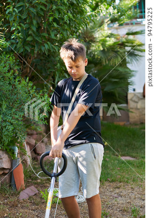 boy with electric mower in the garden boy with electric mower in the garden 94795225