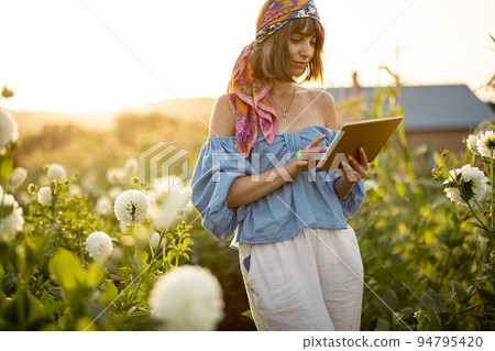 Woman with a digital tablet on flower farm outdoors 94795420
