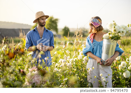 Man and woman pick up flowers at farm outdoors Man and woman pick up flowers at farm outdoors 94795470