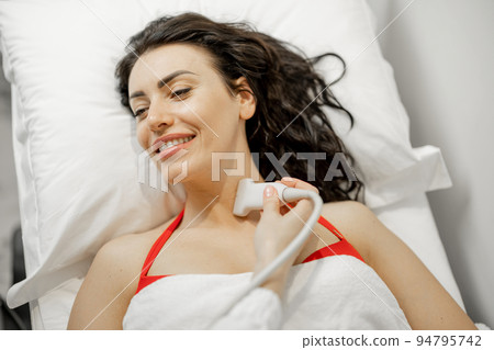 Woman examining thyroid gland with ultrasound Woman examining thyroid gland with ultrasound 94795742
