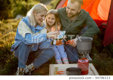 Couple with little girl cooking dried-food for hiking at campsite Couple with little girl cooking dried-food for hiking at campsite 94796313