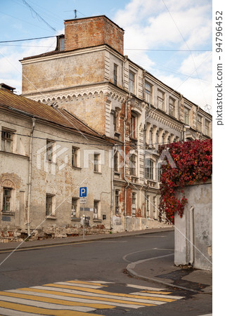 old brick house with weathered walls in city street 94796452