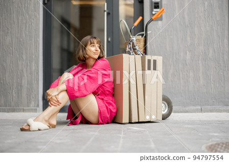 Woman with parcels near residential building 94797554