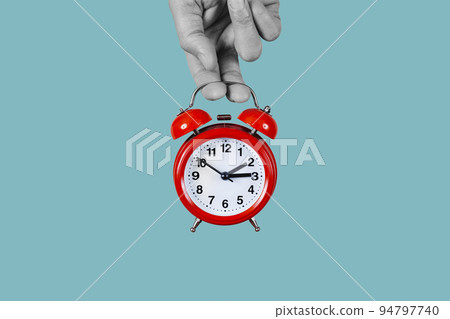 red alarm clock being set backwards or forwards 94797740
