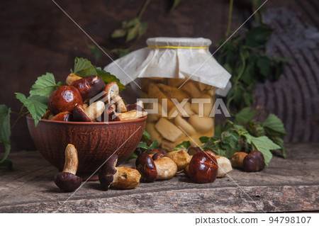 Pile of Imleria Badia or Boletus badius mushrooms commonly known as the bay bolete with canned mushroom in glass jar on vintage wooden background.. Pile of Imleria Badia or Boletus badius mushrooms commonly known as the bay bolete with canned mushroom in glass jar on vintage wooden background.. 94798107