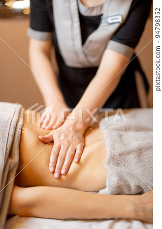 Masseuse performs professional abdominal massage for a woman 94798352