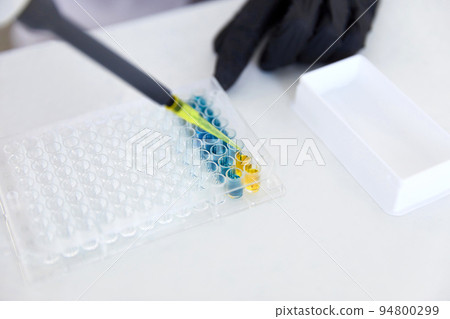 Lab Worker Adding Liquid to Test Tubes 94800299