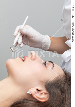 Dental check up in dential clinic. Dentist examining patient teeth with dental mirror during dental check up 94800336