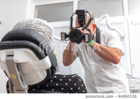 Dentist photographing patient's teeth for medical record before and after surgery in dentist office 94800338