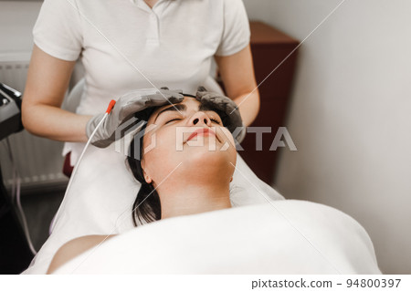 Microcurrent therapy. Cosmelotologist makes stimulating facial massage with electric gloves. Lymphatic drainage massage.. Microcurrent therapy. Cosmelotologist makes stimulating facial massage with electric gloves. Lymphatic drainage massage.. 94800397