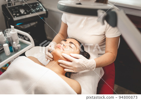 Cosmetologist massages the client's face.. Cosmetologist massages the client's face.. 94800873